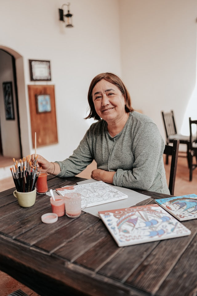 female artist sit in front of a craft table and see the camera